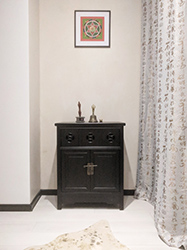 Beige heavy silk curtains with golden hieroglyphs to complement an Oriental cabinet and Tibetan mandala on the wall.